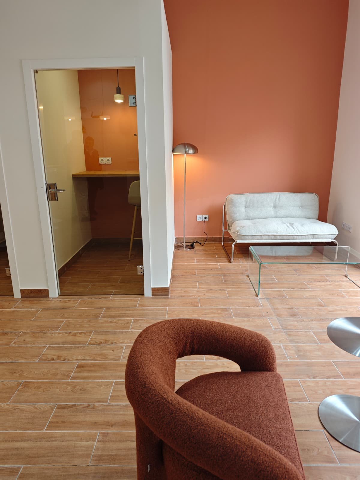 Zona lounge con sillon y pared terracota